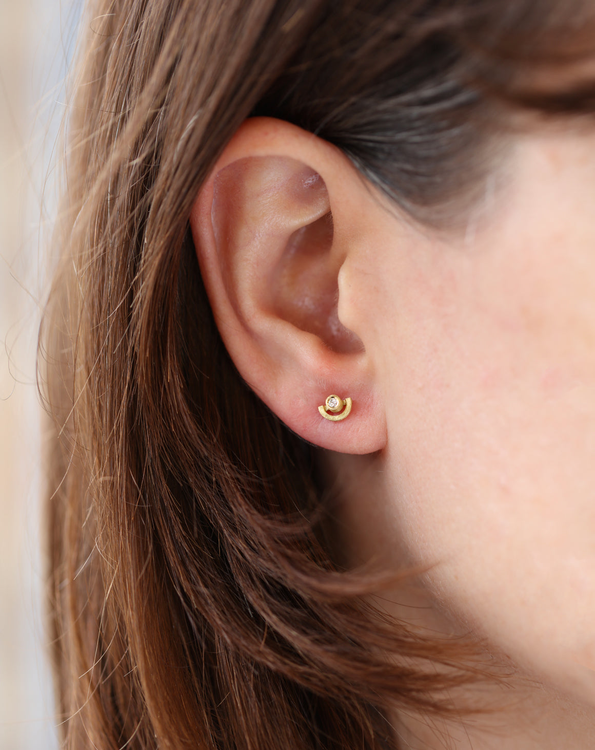 Delicate ear studs with white diamonds and semicircle detail. 18ct yellow gold, textured finish. Worn on ear.