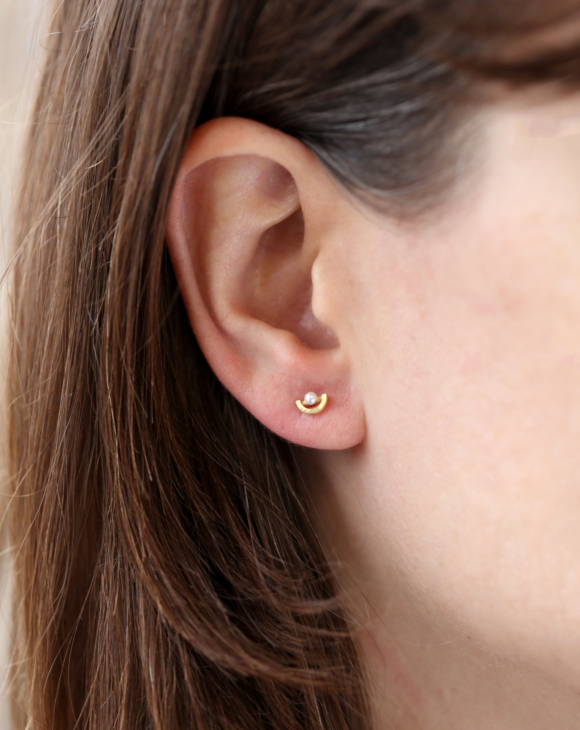 Ear studs with white pearls and semi circle detail. 18ct yellow gold, textured finish. Worn in ear.