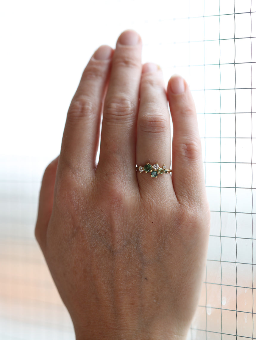 Asymmetric cluster style ring with green sapphires and white diamonds. 18ct yellow gold, satin finish. On hand.