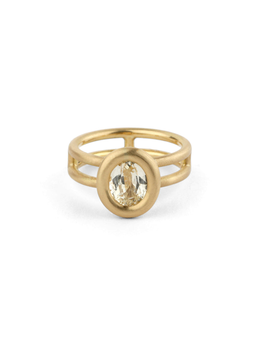 Oval pale yellow sapphire ring with a heavy rounded bezel setting and double band. 18ct yellow gold, satin finish.