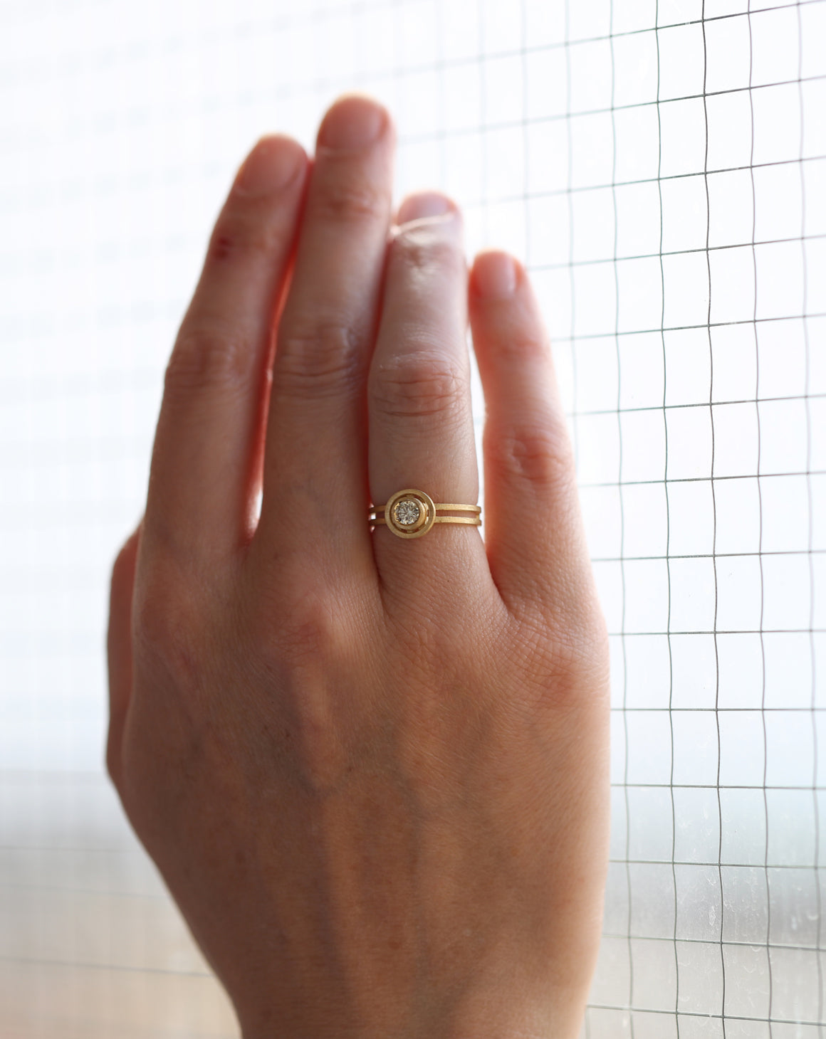 Round champagne diamond ring with circular detail and double band. 18ct yellow gold, textured finish. On hand.