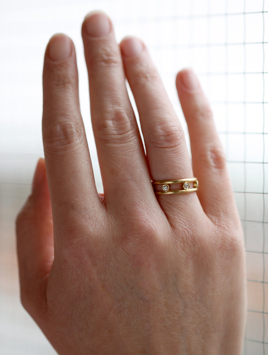 Ring with double band and seven white diamonds set in between. 18ct yellow gold, satin gold. On hand.