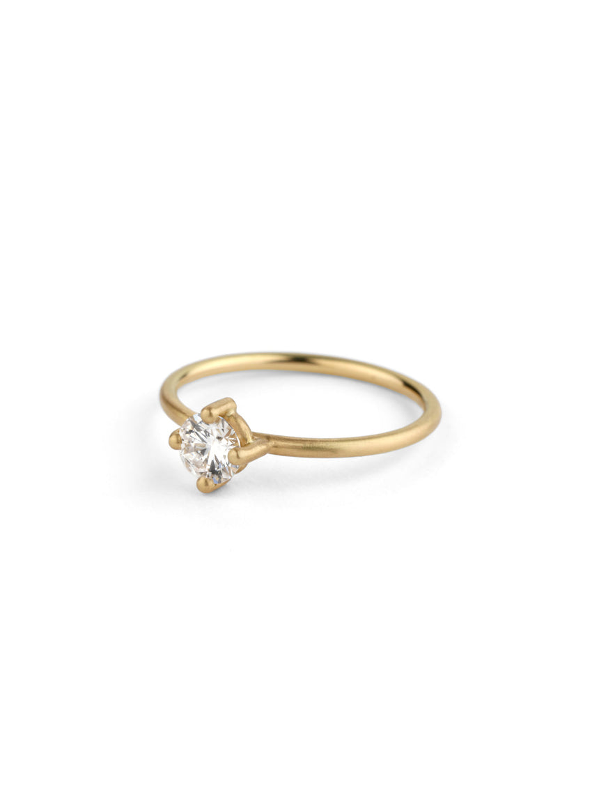 Solitaire ring with round white diamond, four claw setting. 18ct yellow gold, polished finish. Side view.