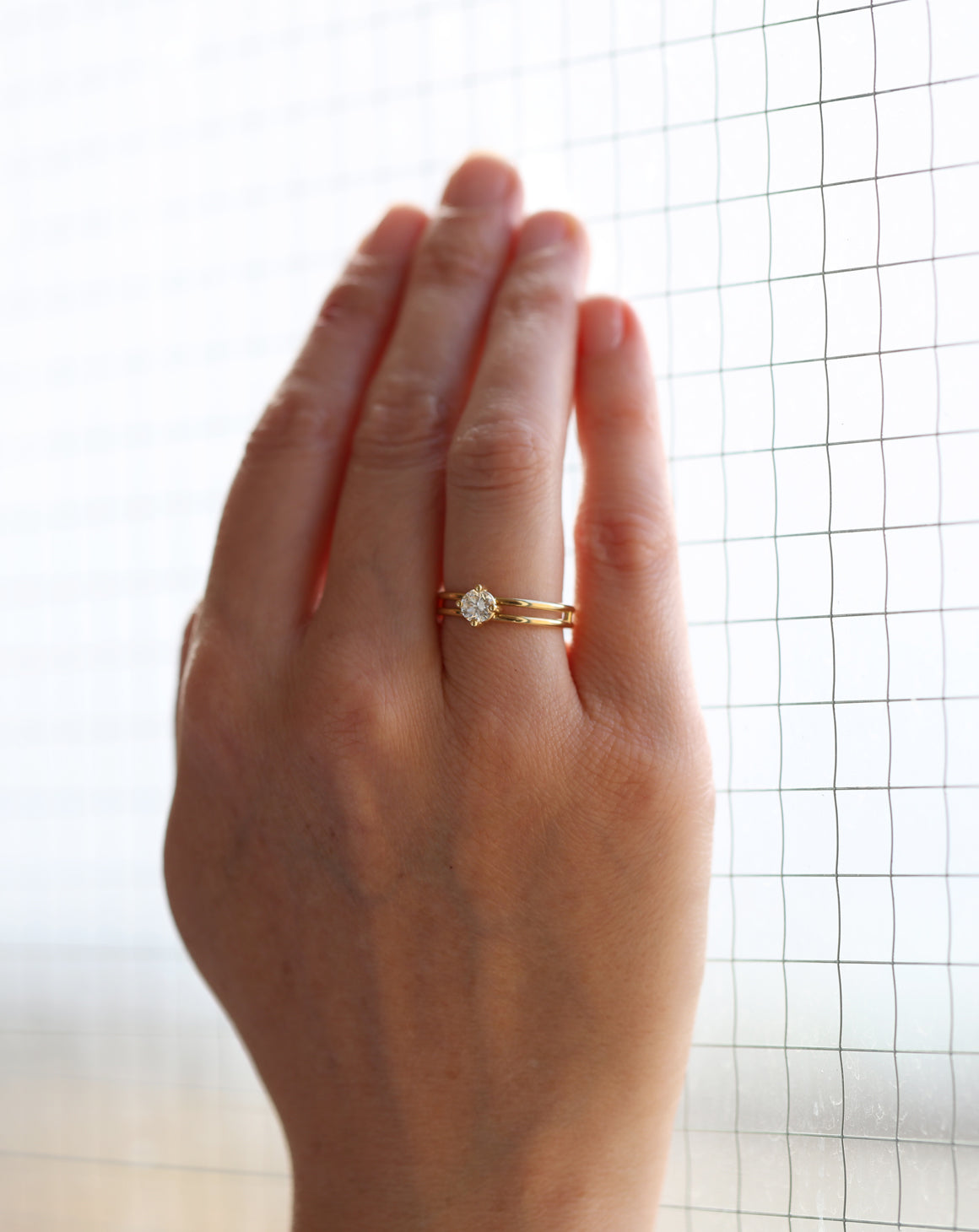 Solitaire ring with round white diamond and double band. 18ct yellow gold, polished finish. Worn on the hand.