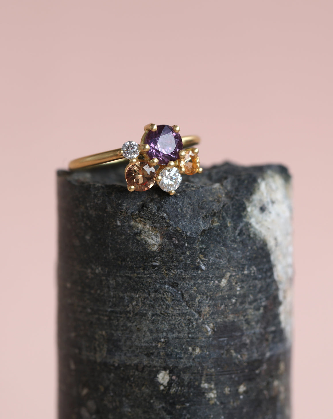 Cluster ring with purple and peach sapphires and white diamonds. 18ct yellow gold, satin finish. On rock.