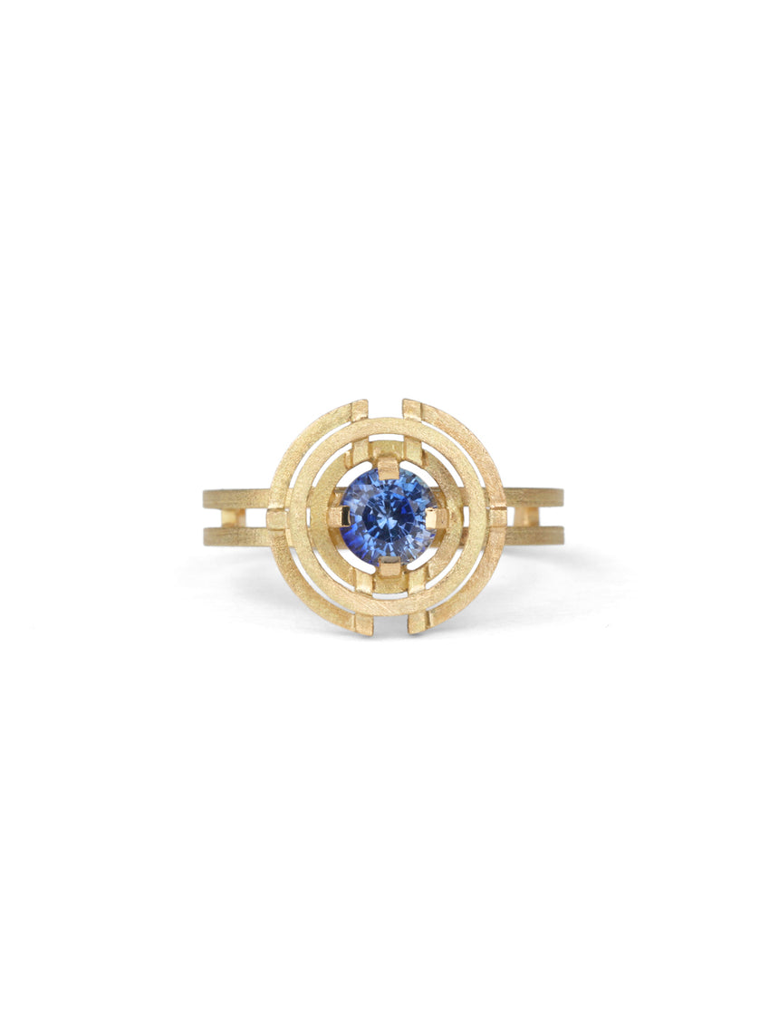 Symmetrically patterned ring with a central blue sapphire. 18ct yellow gold with textured finish.