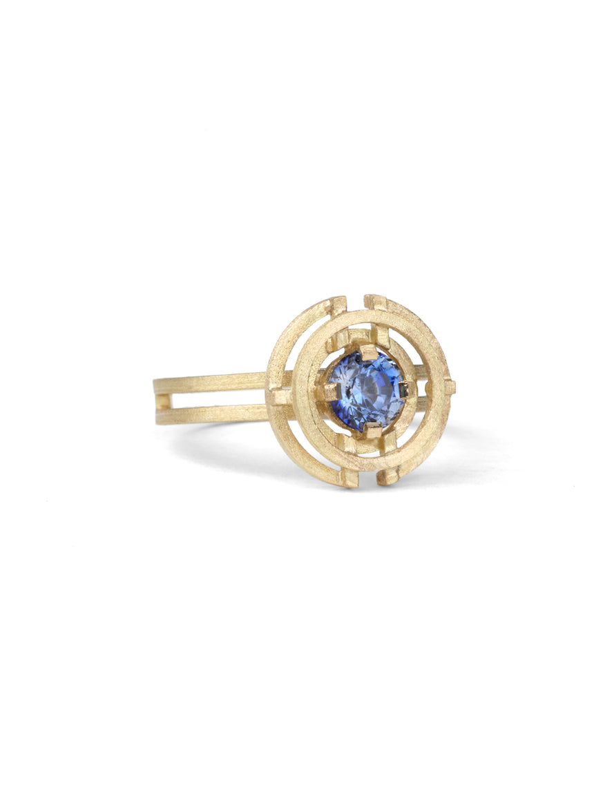 Symmetrically patterned ring with a central blue sapphire. 18ct yellow gold with textured finish.
