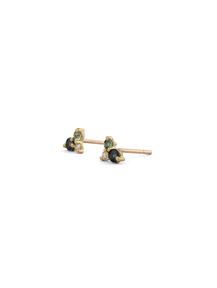 Ear studs with a cluster of three gemstones, a blue and green sapphires and white diamonds. Side view.
