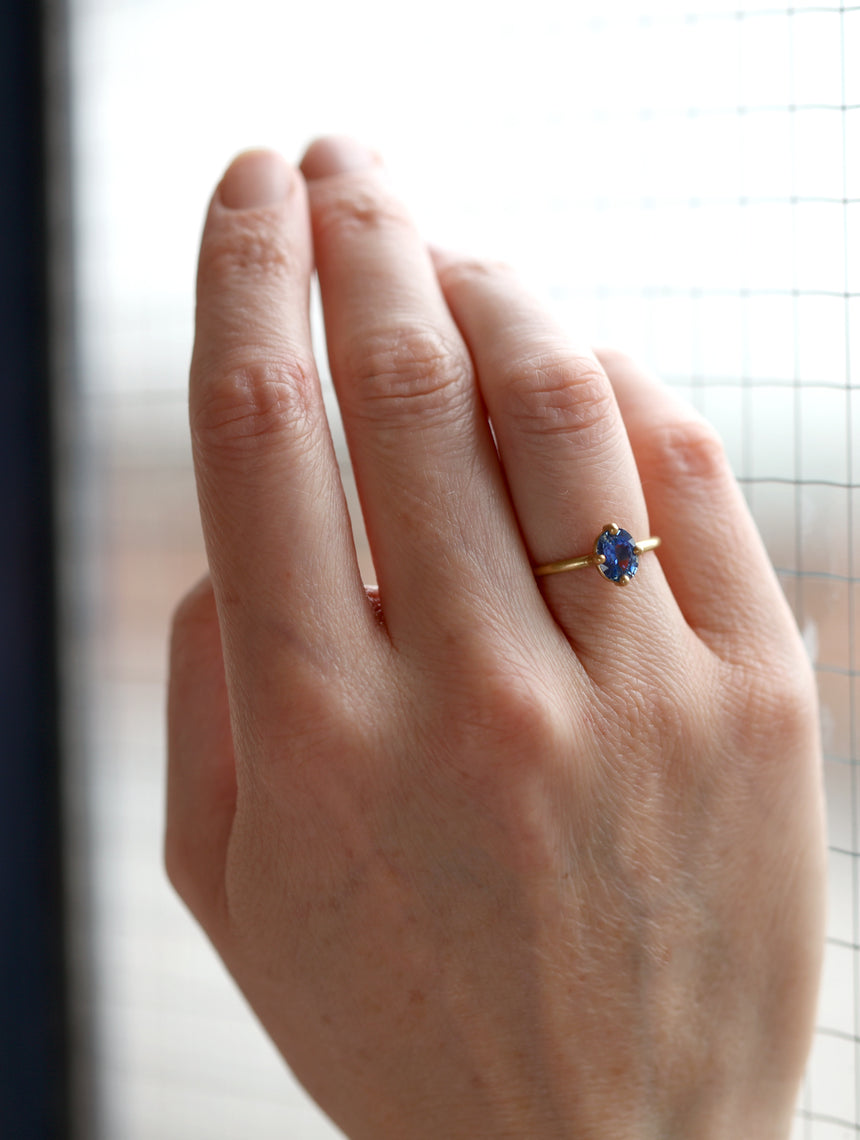 Oval blue sapphire ring, solitaire four claw setting. 18ct yellow gold with a satin finish. On hand.