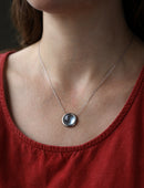 Circular Aquamarine and 18ct white gold necklace worn on neck.