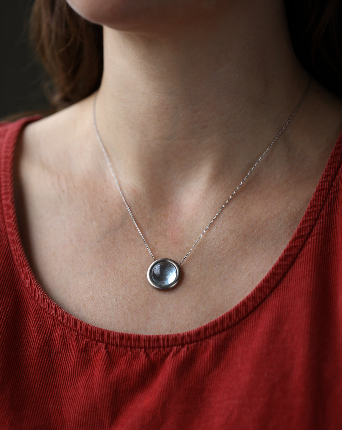 Circular Aquamarine and 18ct white gold necklace worn on neck.