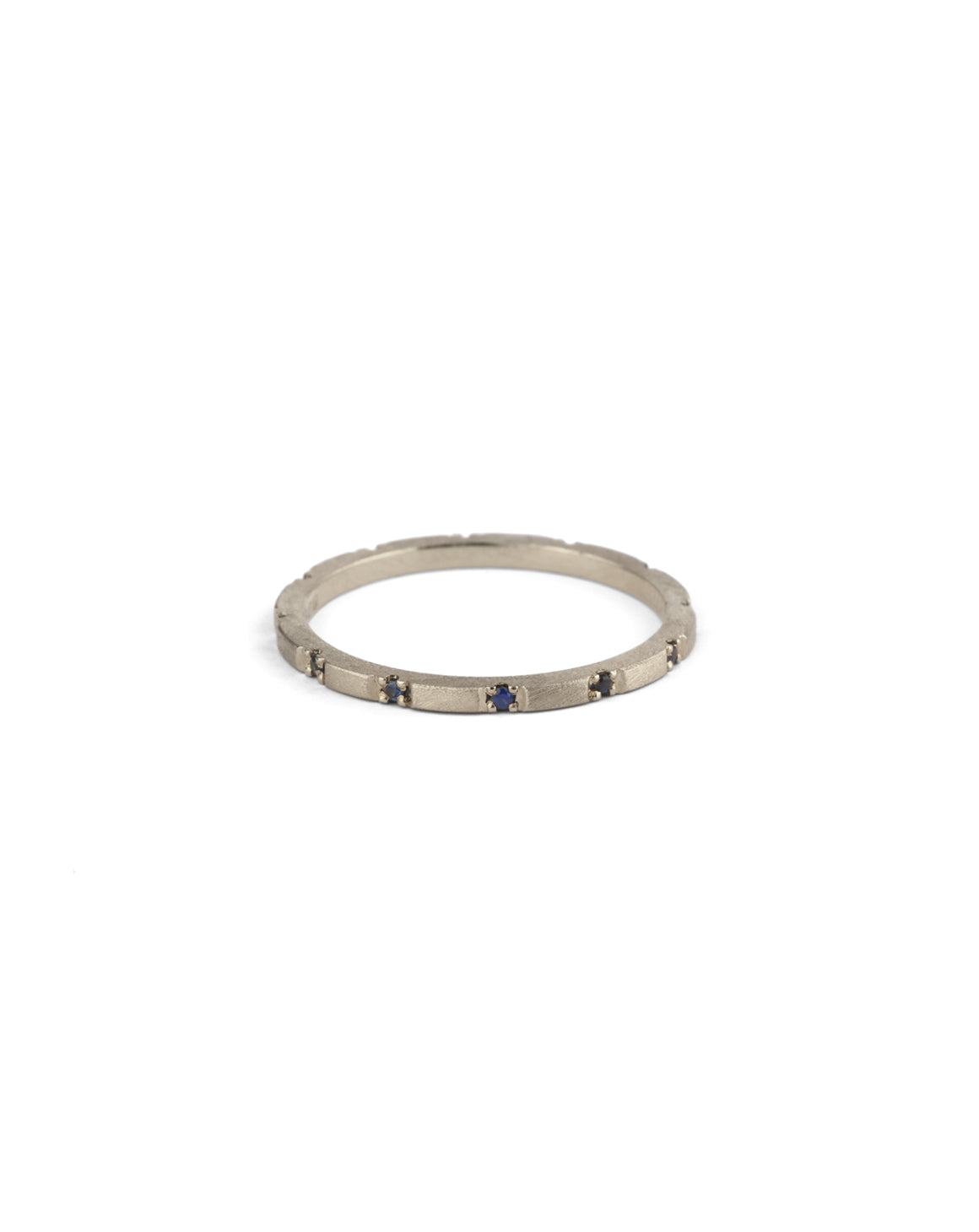 Fine gold band with set with small dark blue sapphires. 18ct white gold textured finish.