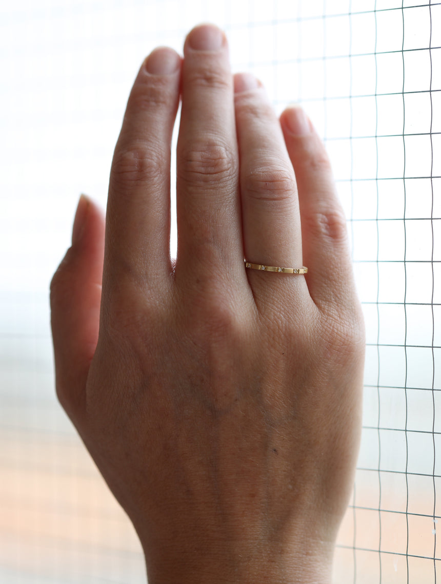 Fine ring band set with tiny white diamonds. 18ct yellow gold, textured finish. On hand.