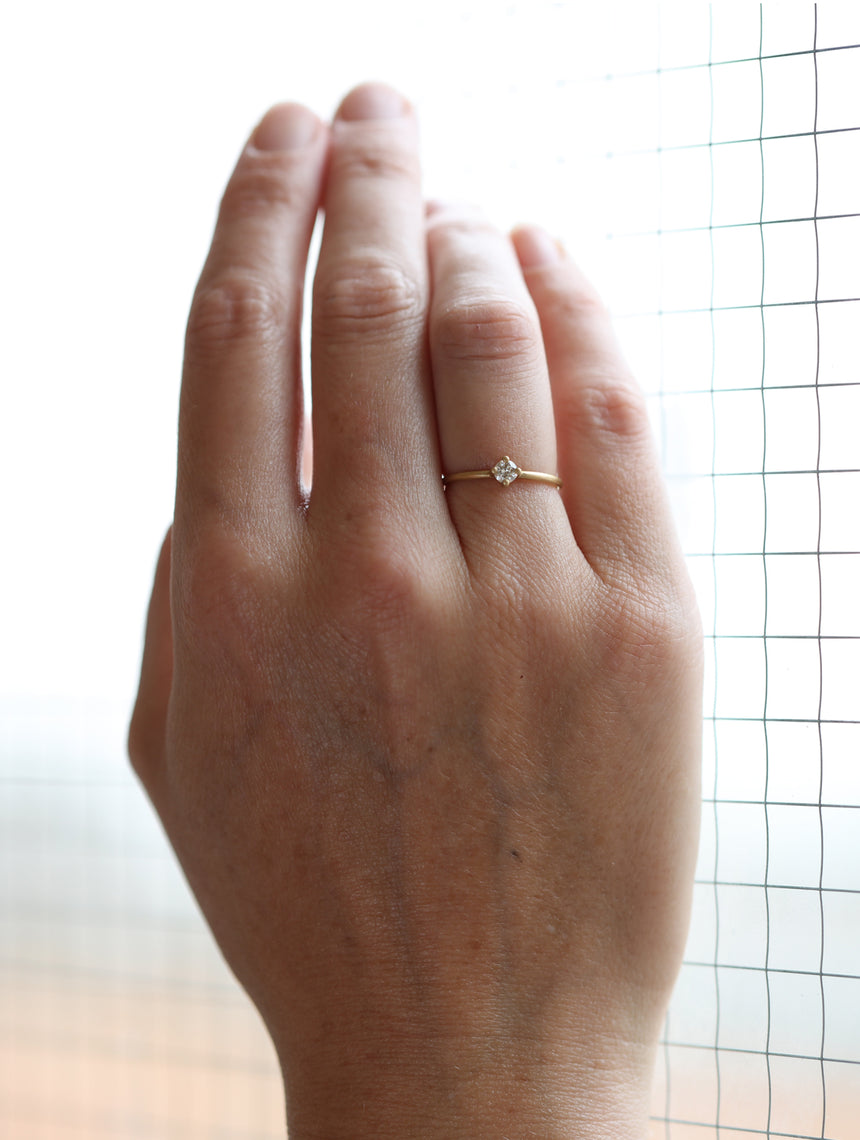 Solitaire ring with round white diamond, four claw setting. 18ct yellow gold, satin finish. On hand.