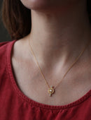 Geometric pendant with circular detail  and three white diamonds. 18ct yellow god, textured finish. Worn on neck.