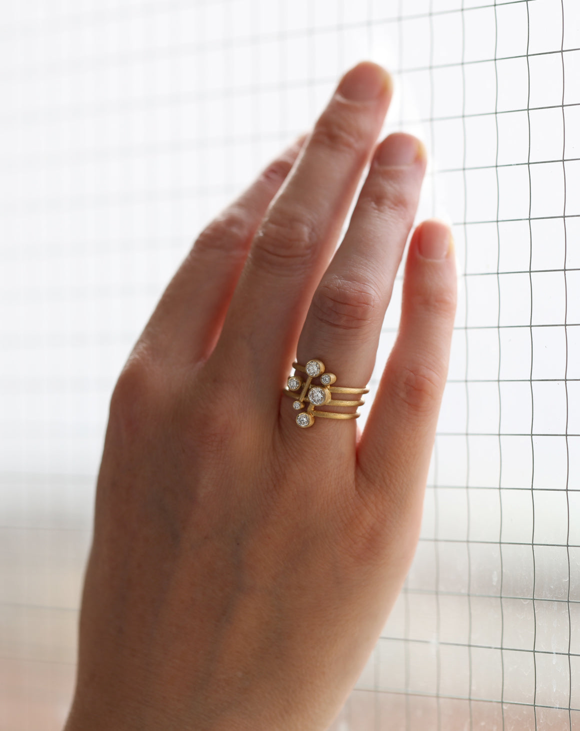 Six diamond wide band ring. Asymmetric configuration on spiral band, 18ct yellow gold textured finish. On hand.