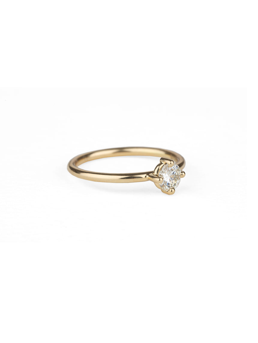 Solitaire ring with round white diamond, four claw setting. 18ct yellow gold, polished finish. Side view.