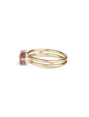 Three stone ring with a pink oval sapphire and two white diamonds. 18ct yellow gold, satin finish. Side view.