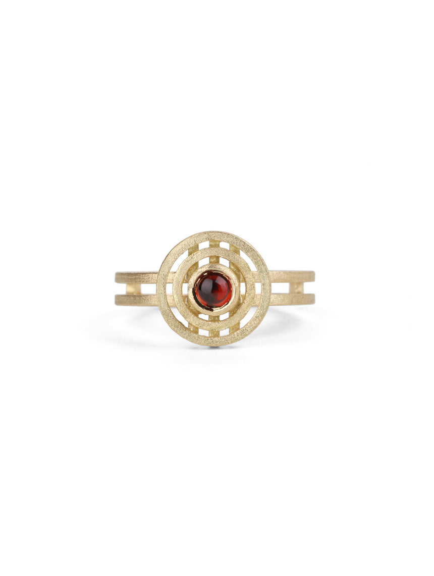 Geometric ring with concentric circular detail. Central round red garnet, 18ct yellow gold, textured finish.