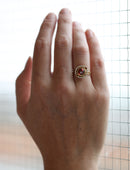 Geometric ring with red garnet and two orange sapphires and a diamond circular surround. 18ct yellow gold, textured finish. On hand.