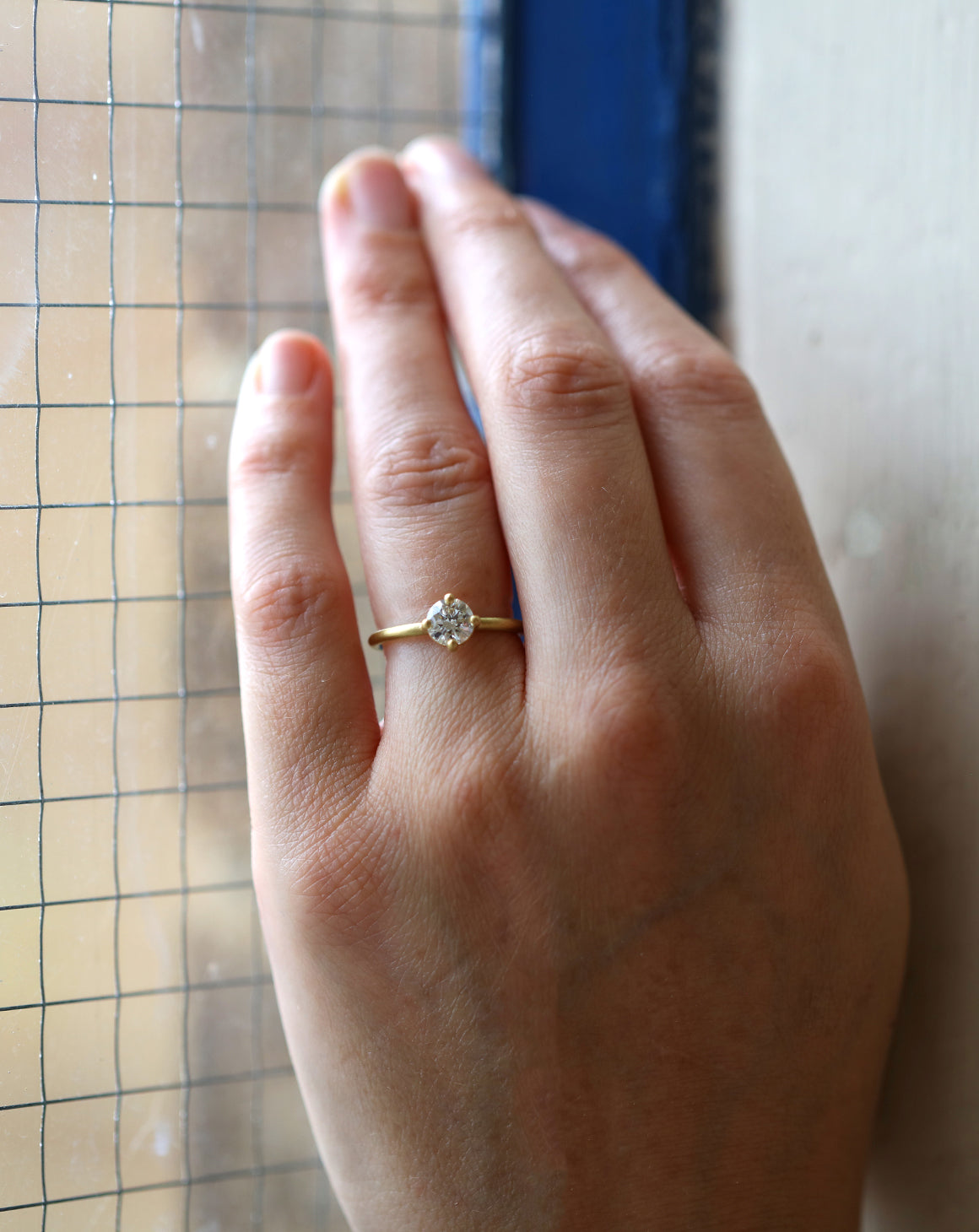 Solitaire ring with round white diamond, four claw setting. 18ct yellow gold, satin finish.