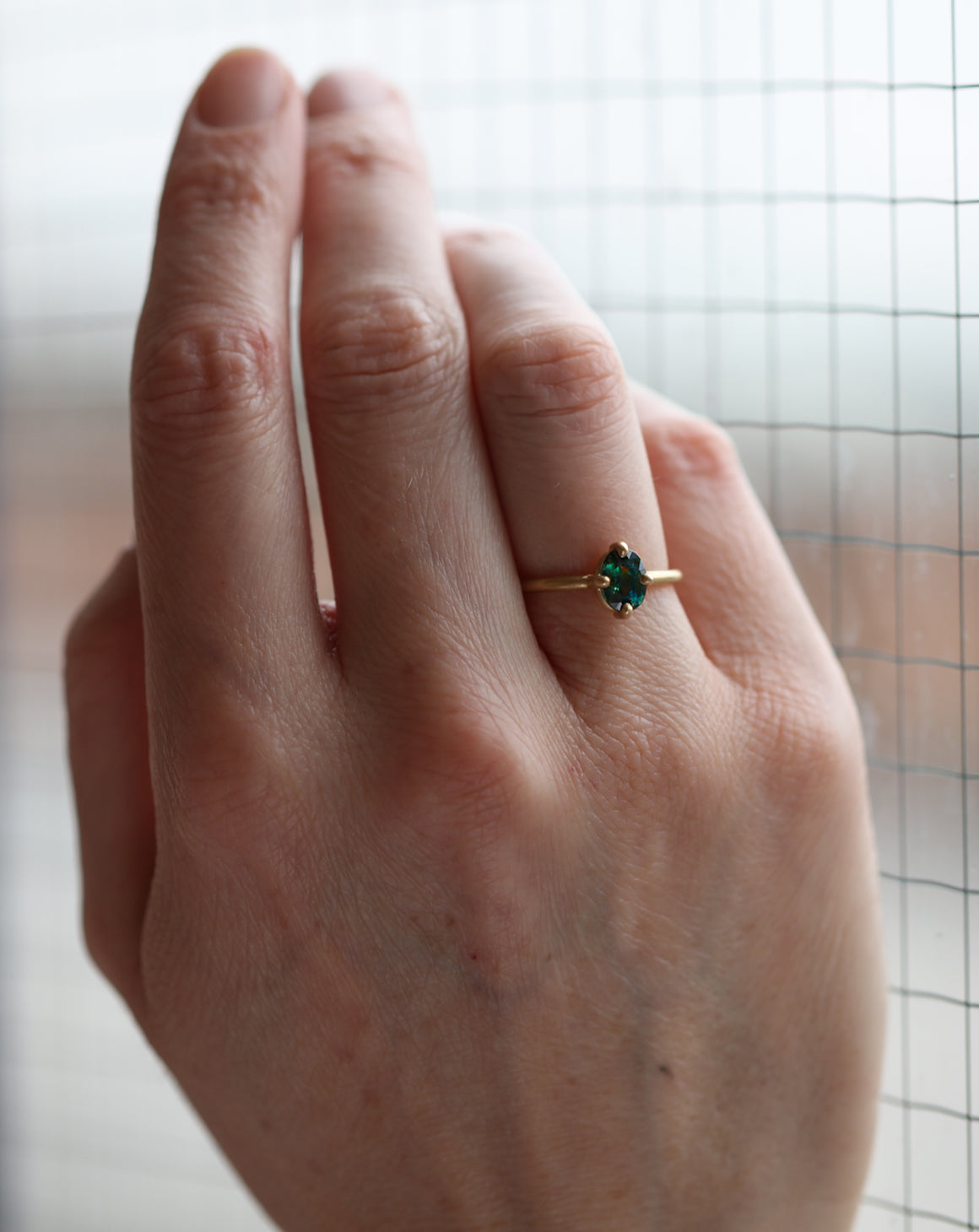 Solitaire ring with oval teal sapphire. 18ct yellow gold, satin finish. On hand.