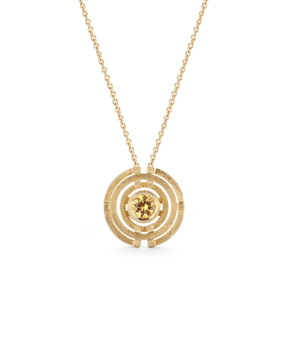 Geometric pendant with concentric circles surrounding yellow sapphire. 18ct yellow gold, textured finish.