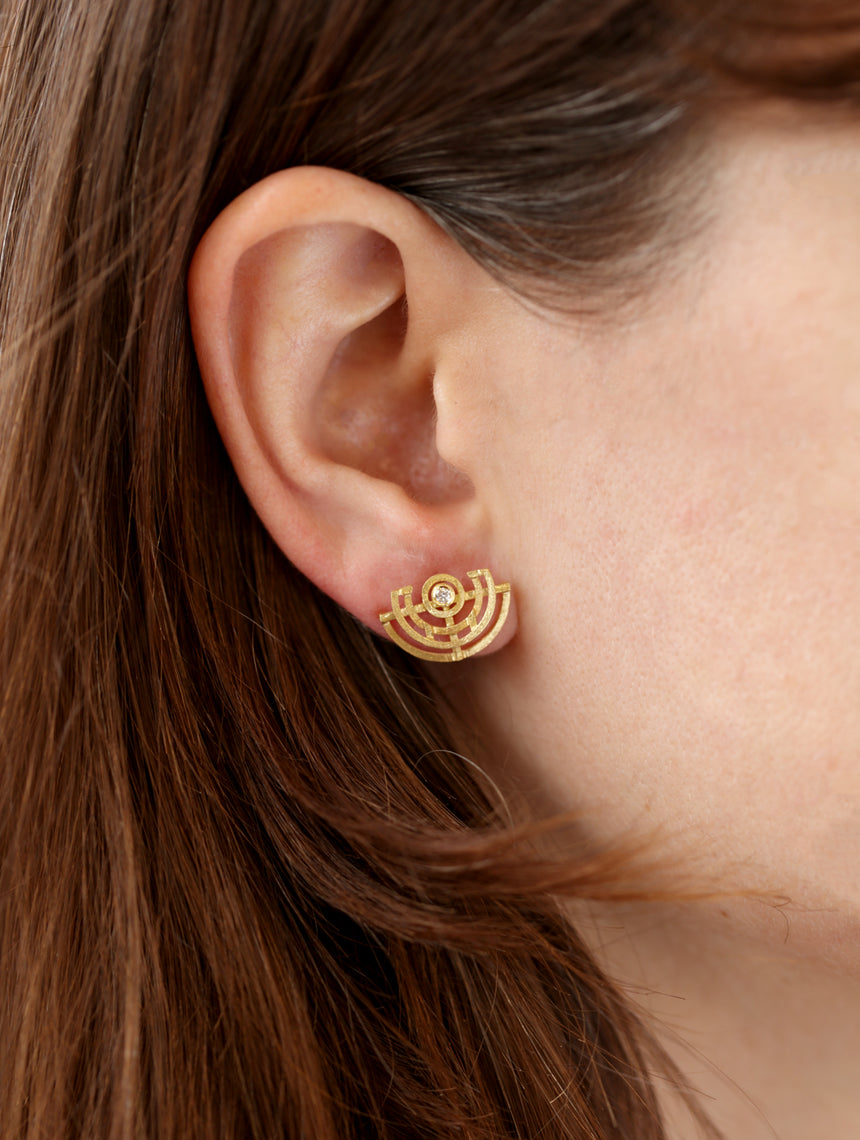 Geometric earrings with semicircular detail and central white diamond. 18ct yellow gold, textured finish. On ear.