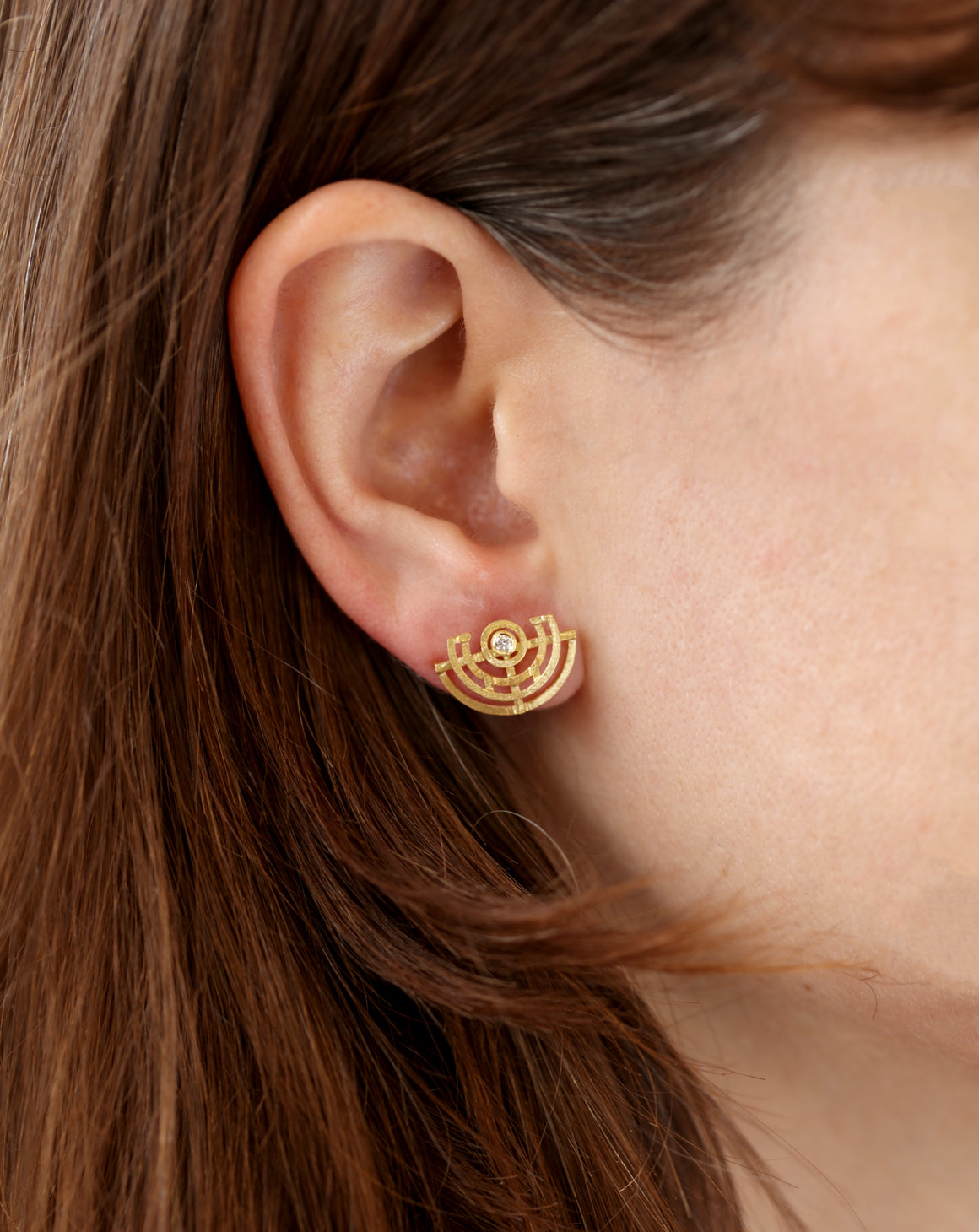 Geometric earrings with semicircular detail and central white diamond. 18ct yellow gold, textured finish. On ear.