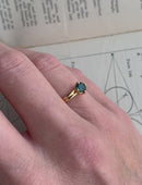 Solitaire ring with teal sapphire and double band. 18ct yellow gold, polished finish. On hand.