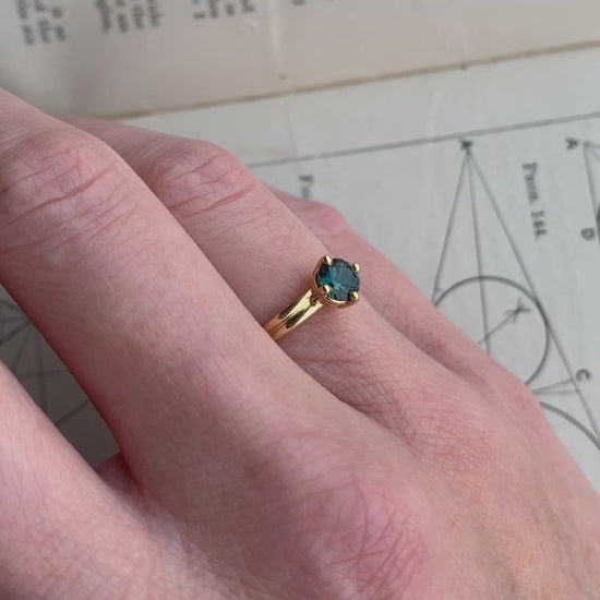 Solitaire ring with teal sapphire and double band. 18ct yellow gold, polished finish. On hand.