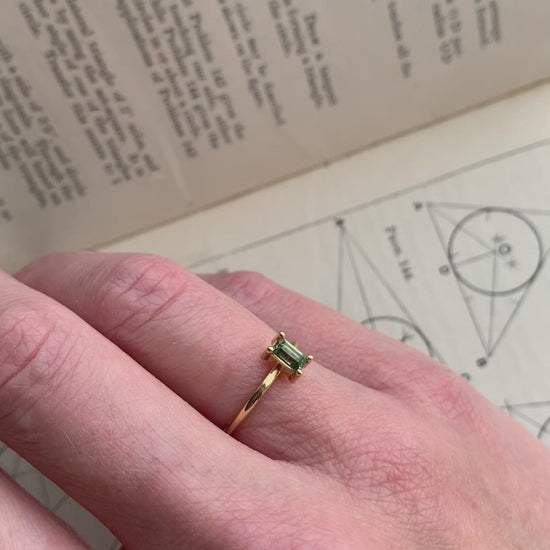 Rectangular green sapphire ring, four claw setting. 18ct yellow gold, polished finish. On hand.