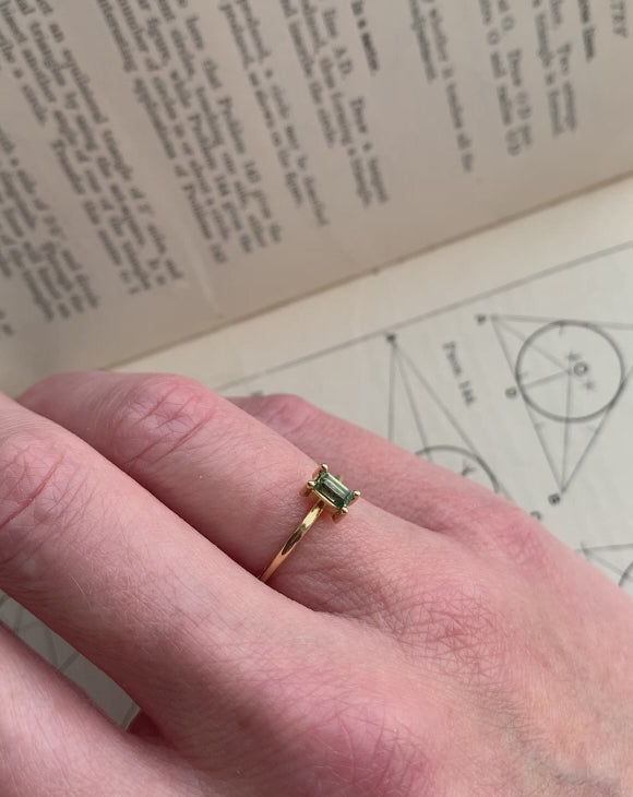 Rectangular green sapphire ring, four claw setting. 18ct yellow gold, polished finish. On hand.