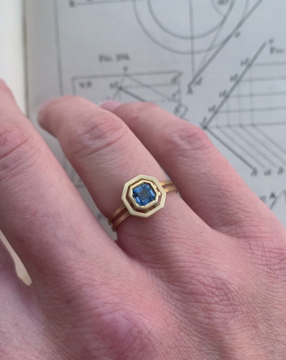 Octagon blue sapphire ring with surround detail and double band. 18ct yellow gold with satin finish. On hand.