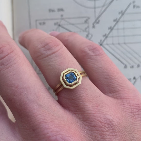 Octagon blue sapphire ring with surround detail and double band. 18ct yellow gold with satin finish. On hand.