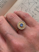 Blue sapphire ring with diamond halo detail. Textured 18ct yellow gold. On hand.