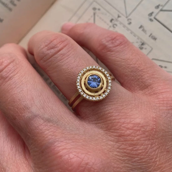 Blue sapphire ring with diamond halo detail. Textured 18ct yellow gold. On hand.
