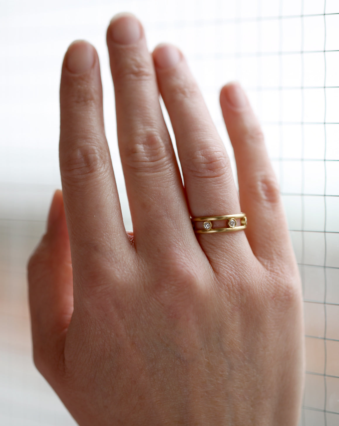 Ring with double band and seven white diamonds set in between. 18ct yellow gold, satin gold. On hand.