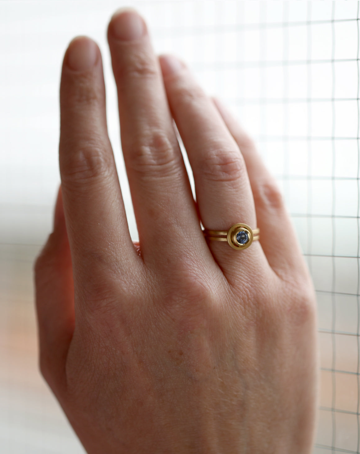 Light yellow sapphire ring with circular detail and double band. 18ct yellow gold, textured finish. On hand.