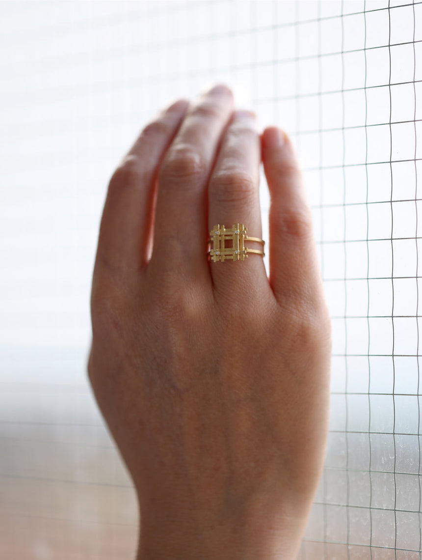 Geometric statement ring with square form and four white diamonds. 18ct yellow gold, textured gold. Worn on hand.