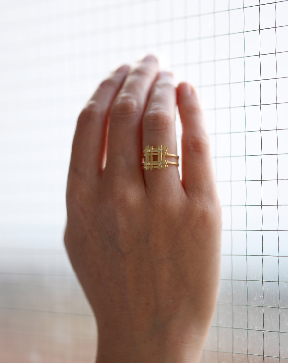 Geometric statement ring with square form and four white diamonds. 18ct yellow gold, textured gold. Worn on hand.